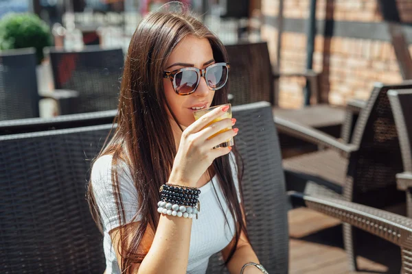 Young girl sitting on the bench and drinking juice. — Stock Photo, Image