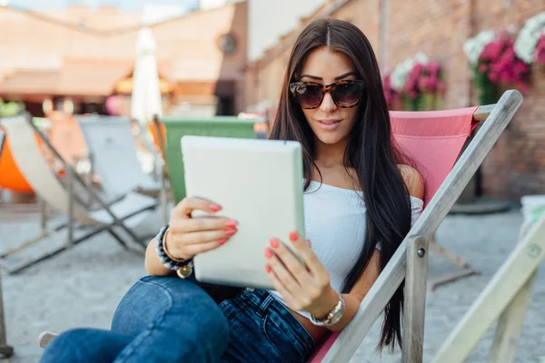 Junges Mädchen sitzt auf der Sonnenbank und benutzt Tablet-PC. — Stockfoto