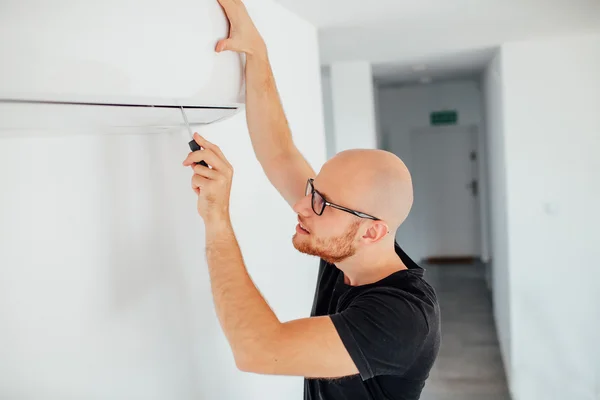 El hombre está reparando un aire acondicionado. Fondo de origen — Foto de Stock