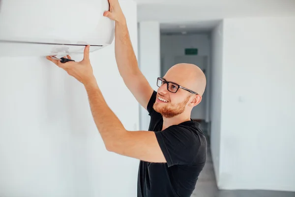 El hombre está reparando el aire acondicionado. Fondo de origen — Foto de Stock