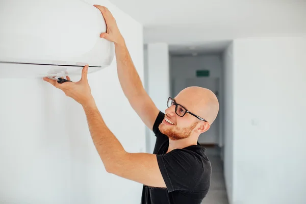 El hombre está reparando el aire acondicionado. Fondo de origen — Foto de Stock