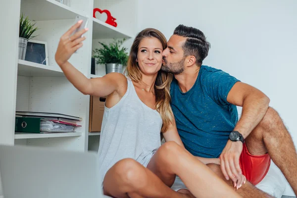 Mujer y hombre están sentados en la cama y tomando selfie por smartp — Foto de Stock