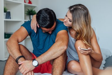 Kadın tezahürat yaparken genç çift yatakta oturmuş bir