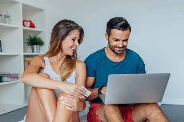 Pareja joven está sentado en la cama y el uso de PC portátil en línea — Foto de Stock