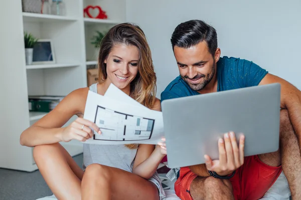 Молодая пара использует ноутбук, пока женщина держит архитектора Лицензионные Стоковые Фото