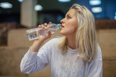 Genç kadın oturuyor ve dalış Şişeden içme. Kapalı b