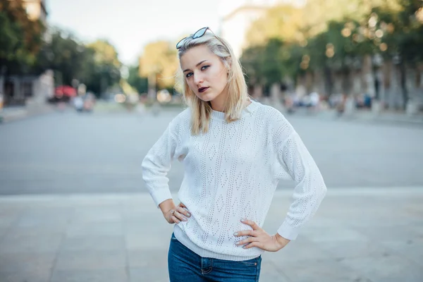 Jovem mulher está de pé e posando para foto. Fundo da cidade . — Fotografia de Stock