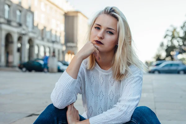 La jeune femme est assise et réfléchit. Contexte de la ville . — Photo