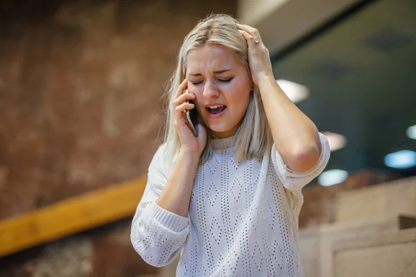 Shocked young woman is sitting at stairs and talking by the phon — Stock Photo, Image