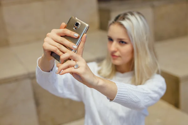 Jonge vrouw is het nemen van een selfie door smartphone. Indoor achtergrond. — Stockfoto
