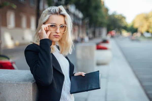 年轻的商界女人着相机的镜头和持有记事本. — 图库照片