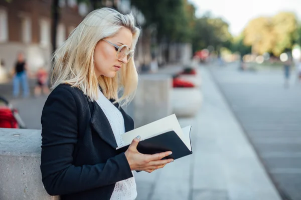 Młoda kobieta jest stojąc i patrząc w Notatniku. CIT — Zdjęcie stockowe
