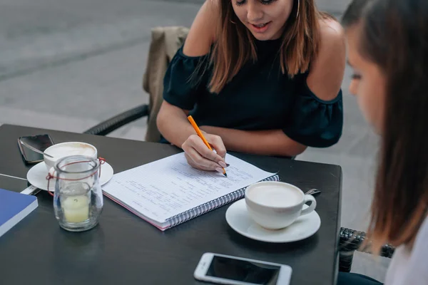 Twee jonge vrouw aan het leren bent bij het openlucht café-restaurant. — Stockfoto