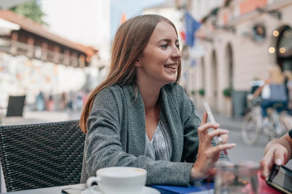 Une jeune femme montre des choses à quelqu'un sur son smartphone. Extérieur — Photo