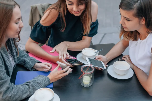 Tres manos de mujer están usando teléfonos inteligentes en la mesa de café . — Foto de Stock