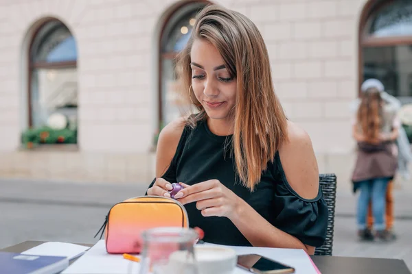 Meisje haalde lippenstift schoonheidsspecialiste bij outdoor cafe restaurant. — Stockfoto