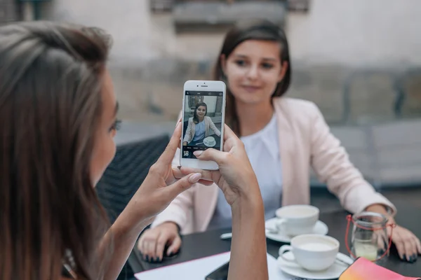 Mladá dívka dělá fotografii svého přítele. Venkovní kavárna čiště — Stock fotografie