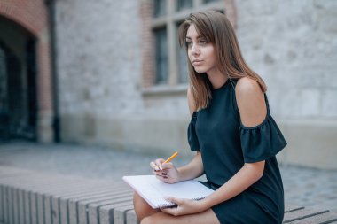 Genç kadın Sokak merdivenleri oturan ve kalem tutan ve 