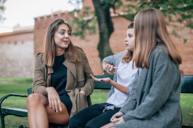 Üç genç kadın bankta oturan ve konuşuyor. Şehir backgro