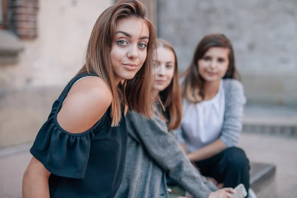 Trois filles sont assises dans les rues et posent pour prendre des photos. C — Photo