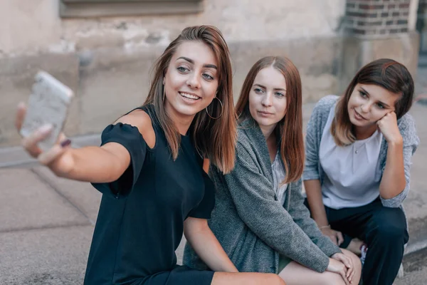 三个女孩坐在街道上楼梯，采取自拍照用 — 图库照片