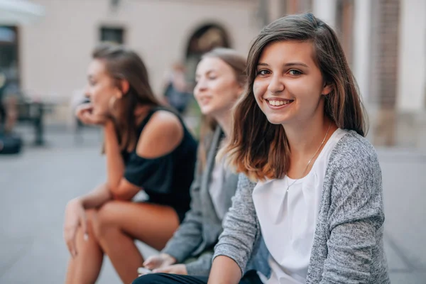 Trois filles sont assises dans les rues et posent pour prendre des photos. C — Photo