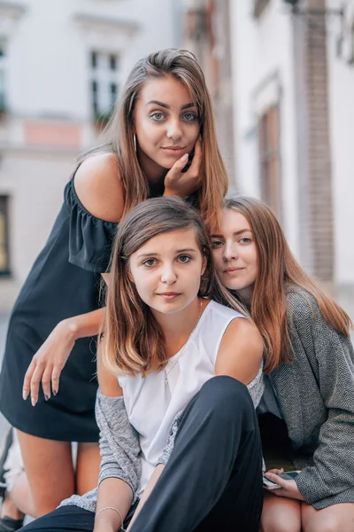 Trois filles sont assises dans les rues et posent pour prendre des photos. C — Photo