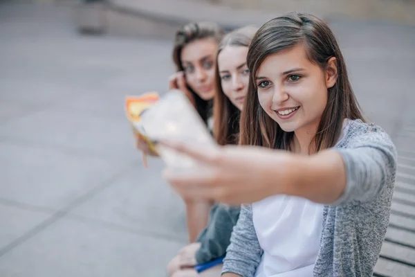 Młode kobiety są siedząc przy ulicy schody i biorąc selfie. Miasto — Zdjęcie stockowe