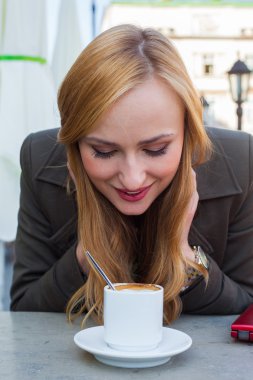 Kafede bir fincan kahveyle oturan bir kadın.