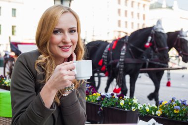 Kafede bir fincan kahveyle oturan bir kadın.