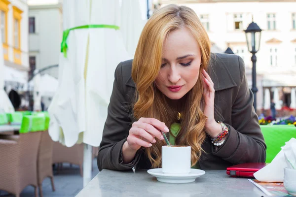 Kobieta siedząca w kawiarni z filiżanką kawy — Zdjęcie stockowe
