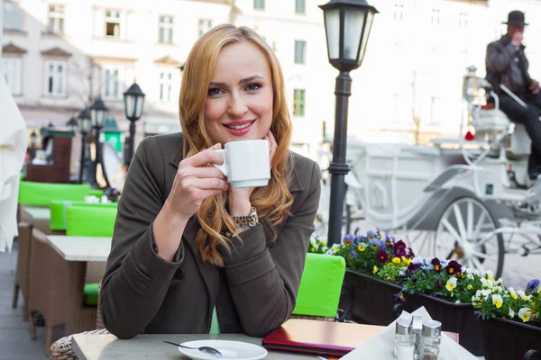 Žena sedí v kavárně s šálkem kávy — Stock fotografie