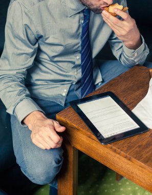 Kahvaltı sırasında tablet üzerinde çalışan iş adamı