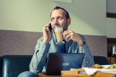 Kahvaltı sırasında cep telefonu kullanan adam