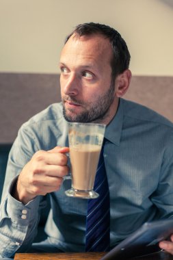 Kahvaltı sırasında tablet üzerinde çalışan iş adamı