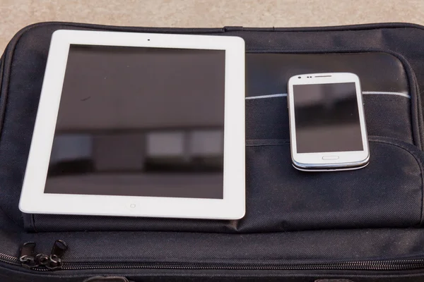 Tablet e telefono cellulare su una borsa — Foto Stock