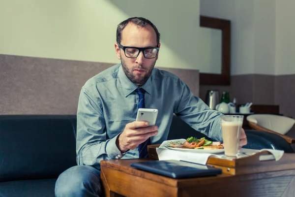 Человек с помощью мобильного телефона во время завтрака — стоковое фото