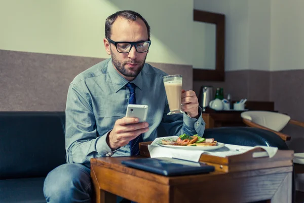 Homem usando telefone celular durante o café da manhã — Fotografia de Stock