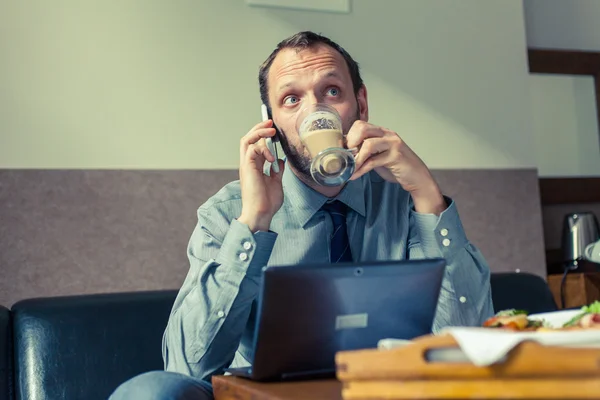 Mann benutzt Handy während des Frühstücks — Stockfoto