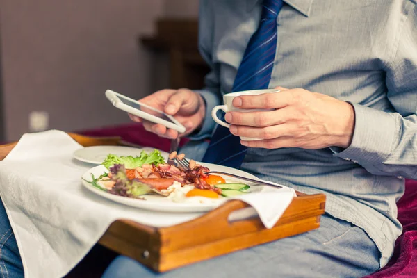 Man met mobiele telefoon tijdens het ontbijt — Stockfoto