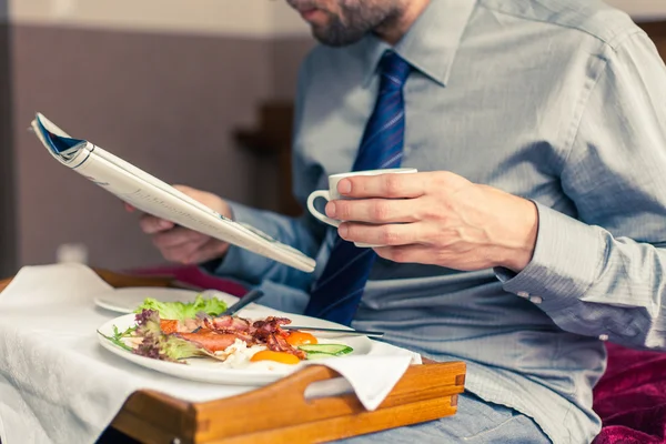 Affärsman läsa tidningen under frukosten — Stockfoto