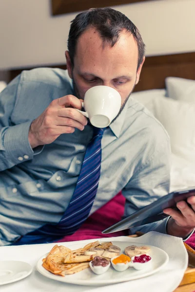 Affärsman som arbetar på tablett under frukosten — Stockfoto