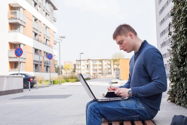 Student met behulp van laptop op Bank — Stockfoto