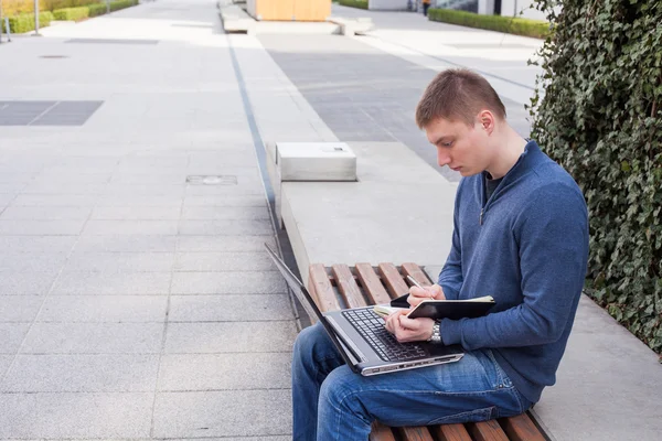 Student met behulp van laptop op Bank — Stockfoto