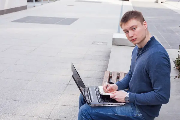 Студент с ноутбуком на скамейке — стоковое фото