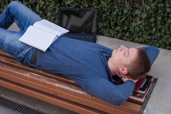 Estudiante descansa con libro en banco de madera —  Fotos de Stock