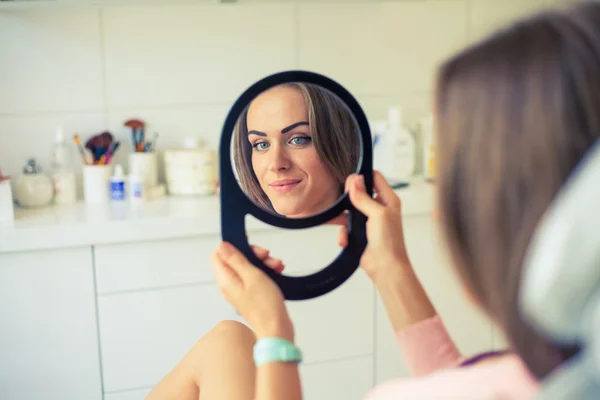 Chica mirando en un espejo en el salón de spa —  Fotos de Stock