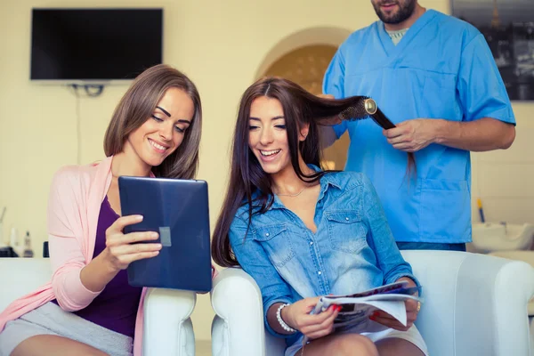 Friends looking at tablet pc in hairdressing salon — Stock Photo, Image