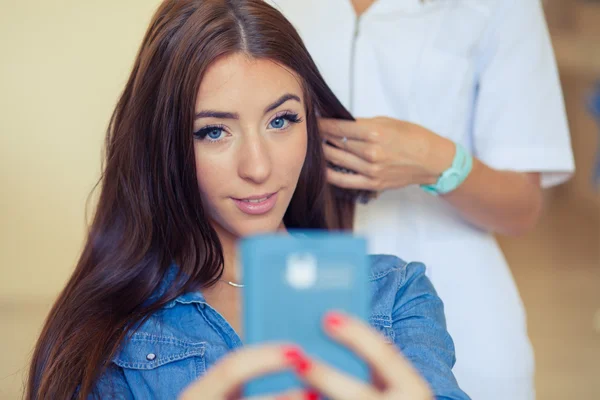 Mulher com smartphone no salão de cabeleireiro — Fotografia de Stock