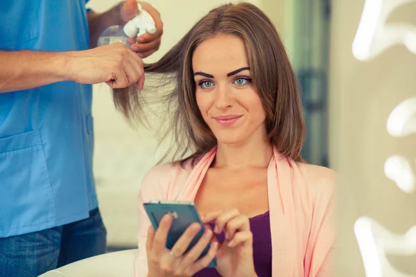 Женщина со смартфоном в парикмахерской — стоковое фото